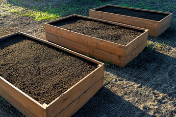 Wooden crates for vegetables lined with agrotextile from the inside and filled with soil. - obrazy, fototapety, plakaty