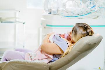 Mom hugs and holds in her arms a premature prematurely born girl in intensive care for a newborn