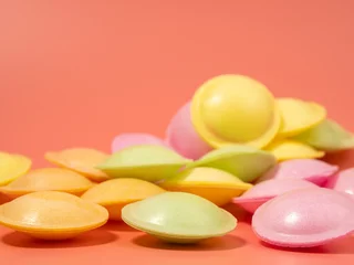 Poster Sweet candies in the shape of a UFO in different colors on a pink background. Flying saucers sugar paper in the shape of a spaceship with sherbet. © Jakob