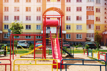 Red colored plastic children slide mounted on playground outdoor. Entertainment children equipment at urban courtyard.