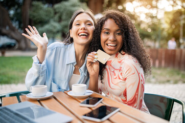 Easy Payments. Two Women Showing Credit Card While Sitting In Cafe Outdoors