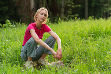 girl teenager squatting on a log in a meadow