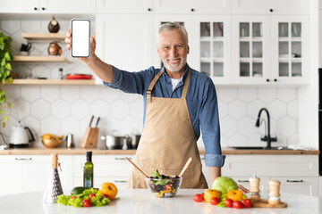Dieting App. Smiling Senior Man Holding Blank Smartphone In Kitchen At Home