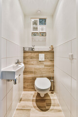 Fototapeta na wymiar a toilet in a bathroom with wood paneled walls and white tiles on the floor, along with a sink