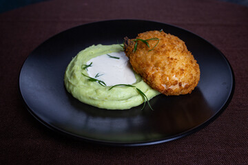 breaded cutlet with mashed potatoes on a black plate in a cafe