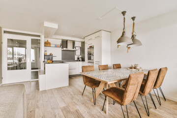 a kitchen and dining area in a house with wood flooring, white walls, wooden floors and large...