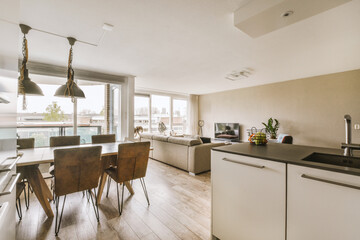 a kitchen and dining area in a house with white walls, wood flooring and large windows looking out onto the street