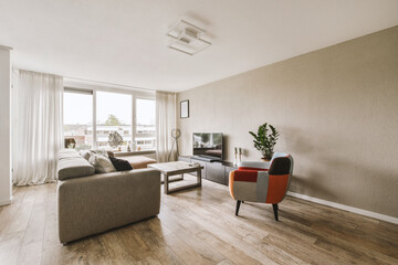 a living room with couches, chairs and television set in the middle of the room looking out onto the street