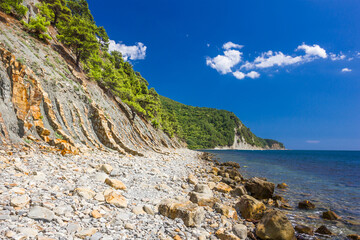 Fototapeta na wymiar Cliffs, rocks and stones on the seashore on a clear day