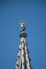 Fototapeta na wymiar Spire at top of Brussels town hall with gilt metal statue of Saint Michael, the patron saint of Belgian City, slaying a dragon or demon. Glorious architecture surrounded by lavish buildings