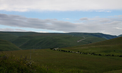 Endless meadow with green grass - pasture in Karachay-Cherkessia in the North Caucasus and cloudy sky and space for copying