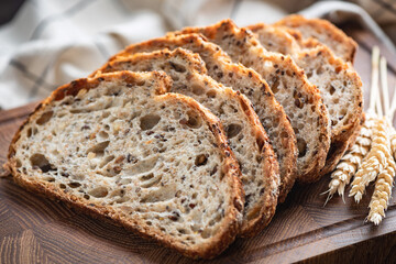 Sourdough bread with seeds sliced on a wooden board, closeup view. Healthy vegan bread
