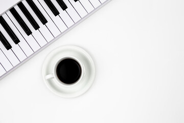 Musical keyboard and a cup of coffee on a white background, flat lay, space for text. Minimalistic...