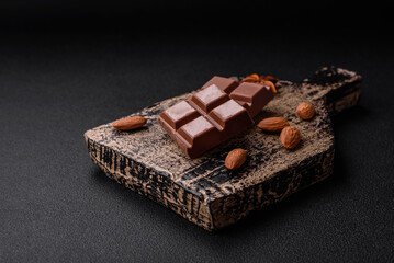 Delicious sweet milk chocolate broken into cubes on a wooden cutting board