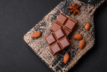 Delicious sweet milk chocolate broken into cubes on a wooden cutting board