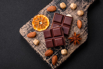 Delicious sweet black chocolate broken into cubes on a wooden cutting board