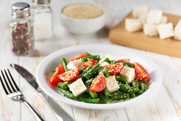 Fresh summer green beans salad bowl with tomatoes, feta, and sesame.