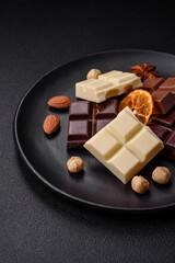 A mix of several types of delicious sweet chocolate broken into cubes on a black plate