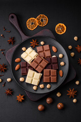 A mix of several types of delicious sweet chocolate broken into cubes on a black plate
