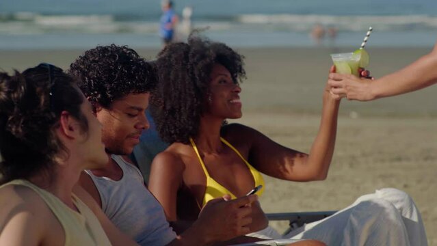 Female employee sells drink on the beach. Nfc cellhone of female buyer with cashless wallet of e-money for pos card reader and checkout. Vacation life of modern people
