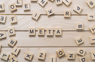 META text on a wooden background with a wooden alphabet