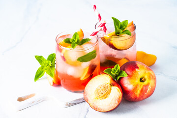 Peach cocktail, iced peach tea, fruit drink, summer beverage with fresh fruits and mint. Close up.