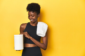 African woman in sportswear with protein powder and towel