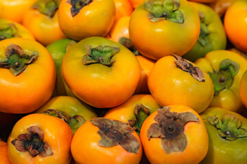 Persimmon in bulk in pile in grocery supermarket, selective focus