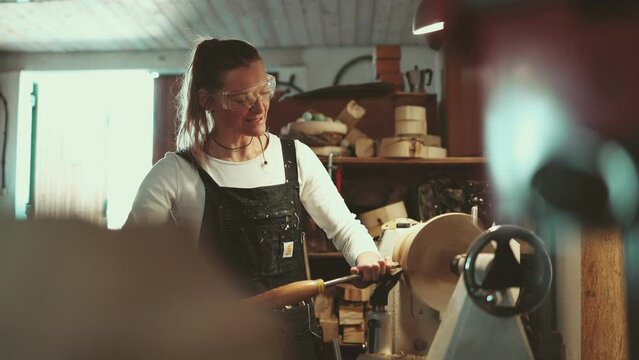 Craftswoman carving wood in a carpentry workshop 
