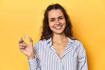 Woman holding an invisible teeth corrector happy, smiling and cheerful.