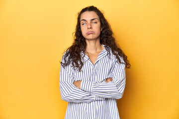 Young Caucasian woman, yellow studio background, tired of a repetitive task.