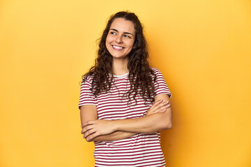 Obraz premium Young Caucasian woman, yellow studio background, smiling confident with crossed arms.