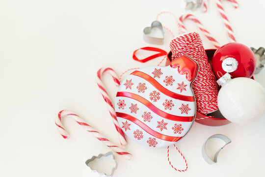 Christmas candies, along with cookie cutters, Christmas tree toys and red thread for gift wrapping, lie on a white table.  Christmas and New Year 2023-2024. Place for an inscription. - Powered by Adobe