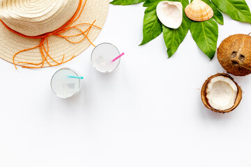 Coconut milk cocktail on the beach with a straw hat