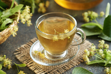 A cup of herbal tea with fresh linden flowers on a table