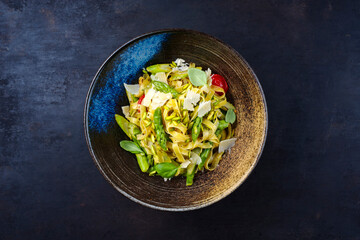 Traditional Italian tagliatelle with green asparagus, tomatoes and sliced pistachios served as a...