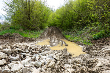 Muddy forest road in nature with tire tracks of tractors and off-road vehicles