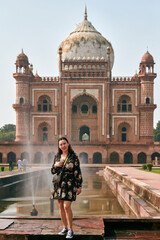 Attractive east asian woman in dress stands in front of tomb of Safdar Jang in New Delhi, India, tattooed young girl full body portrait in indian touristic spot, woman tourist in India - obrazy, fototapety, plakaty