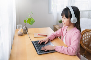 Portrait of Asian girl using computer to learn online live lessons in elementary school. Student boy studying in primary Children with gadgets at home. Education knowledge, technology internet network