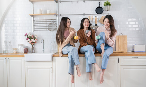 Portrait of young beautiful asian woman group of friends hands holding coffee cup morning time in kitchen room Happy cheerful relax in winter. Korean asian makeup wakeup university together lifestyle