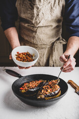 Preparing eggplants stuffed with ground beef, tomatoes and spices