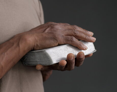 man praying with hand on bible on grey background with people stock image stock photo