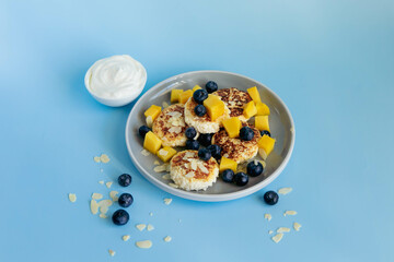 Breakfast with cheesecakes and berries on blue background