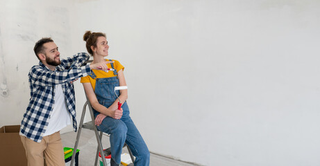 Happy couple during renovating works in house discuss creativity design ideas. Planning redecoration new interior. banner with copy space