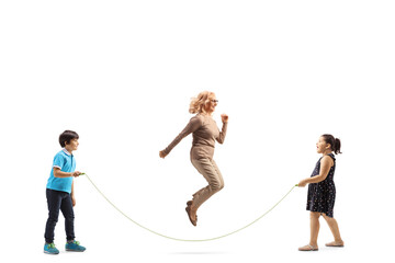 Full length profile shot of a boy and girl holding a rope and a woman jumping