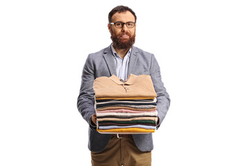Bearded man holding a pile of folded clothes and smiling at camera