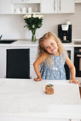 Child waiting for food on the kitchen. Happy little girl smiling on the white kitchen.