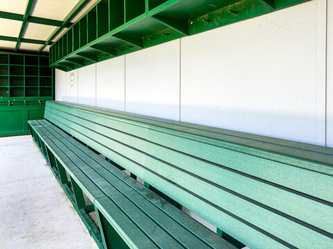 typical nondescript high school baseball, softball dugout with green bench and gray walls. No people visible. Not a ticketed event. - Powered by Adobe