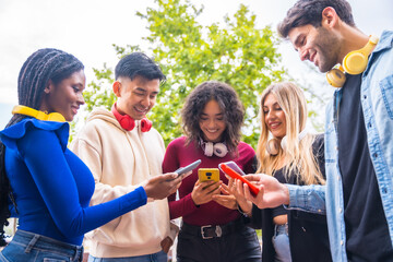 Low angle view of a group of young multi-ethnic teenage friends using cell phones on campus in the city. Technology addicted millennial community concept. Social Media communication generation Z
