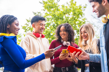 A group of young multi-ethnic teenage friends using cell phones in the city campus. Technology addicted millennial community concept. Social Media communication generation Z